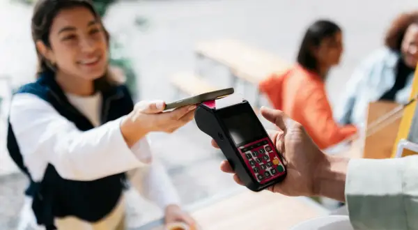 Junge Frau bezahlt kontaktlos mit ihrem Smartphone. Schnelle und einfache mobile payment Transaktion.