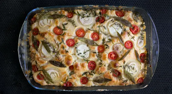 Goldbraune Focaccia mit Kirschtomaten, Zwiebelringen und Kräutern. Ein köstliches Beispiel für Focaccia Rezepte.