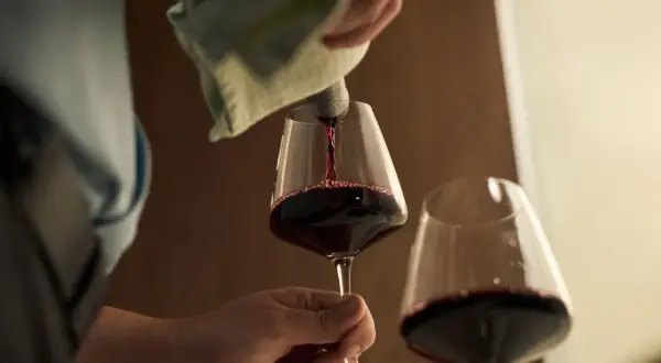 Czerwone wino nalewane do kieliszka. Czy wino jest zdrowe? Debata trwa, ale kieliszek w dłoni wygląda kusząco.