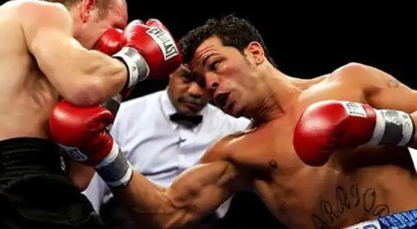 Boxer lands a powerful body shot, his opponent recoils as the referee watches closely.
