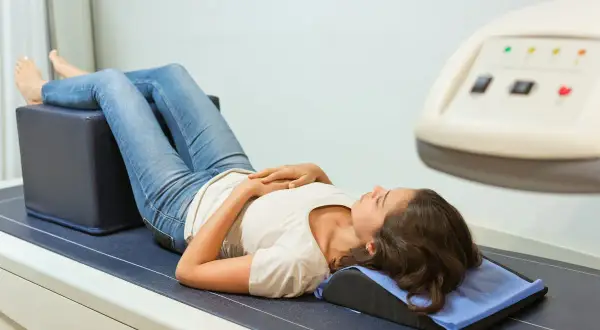 Jeune femme allongée pour un examen, peut-être pour évaluer une ostéopénie et ses douleurs associées.