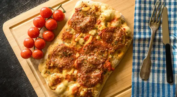 Pizza pepperoni z pomidorkami na desce. Zastanawiasz się, ile kalorii ma pizza 30 cm?