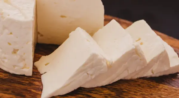 Queso de cabra fresco y cortado en cuñas sobre tabla de madera. Ideal para ensaladas, con pocas calorias.