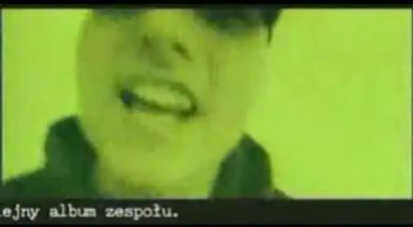 Fragment klipu zespołu Kaliber 44. Widać twarz rapera na zielonym tle. Tekst: "ejny album zespołu.
