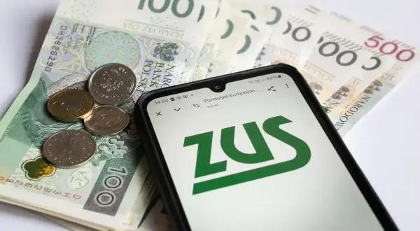 Złotówki i monety na tle ekranu telefonu z logo ZUS. Sprawdź, ile jest zasiłku pogrzebowego.