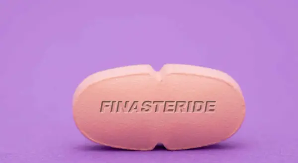 Różowa tabletka z napisem FINASTERIDE. Szukasz co na prostatę bez recepty? To może być rozwiązanie.
