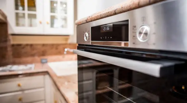 Forno moderno in acciaio inossidabile, con display digitale e manopole. Ideale per chi cerca come pulire il forno incrostato senza fatica.
