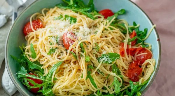 Spaghetti mit Rucola, Kirschtomaten und Parmesan in einer Schüssel.