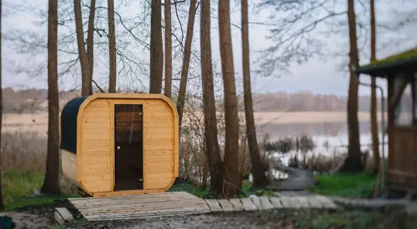 Drewniana sauna w lesie nad jeziorem.