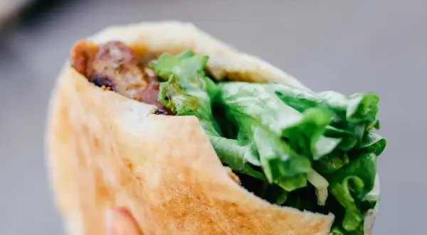Kebab w bułce z mięsem i świeżą sałatą.