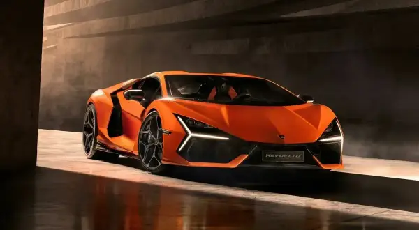 Pomarańczowy Lamborghini Revuelto błyszczy w świetle, gotowy do jazdy.