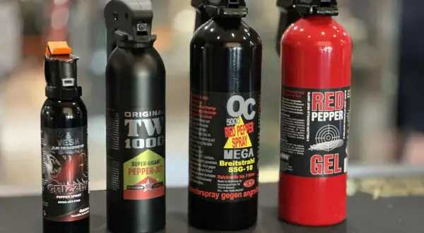 Cztery różne pojemniki z gazem pieprzowym, w tym jeden czerwony z napisem "RED PEPPER GEL".