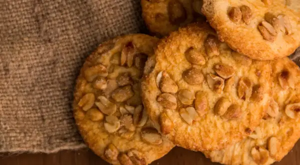 Knusprige erdnuss schoko cookies, verlockend auf Jute und Holz arrangiert.