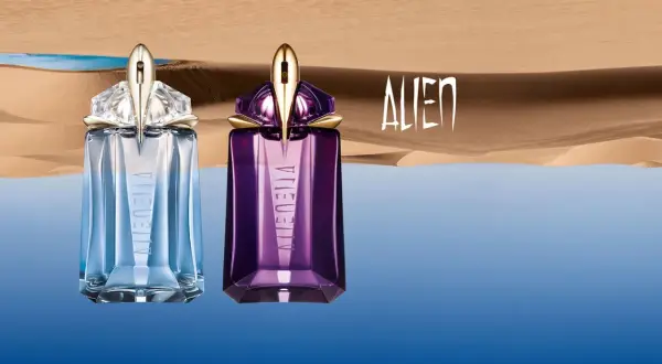 Dwa flakony Mugler Alien EDT: jeden błękitny, drugi fioletowy, na tle pustynnego krajobrazu z wodą.