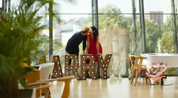 Para zapatrzona w siebie przy literach "MARRY" w nowoczesnym wnętrzu z widokiem na miasto. Idealne miejsce na zaręczyny Polska.