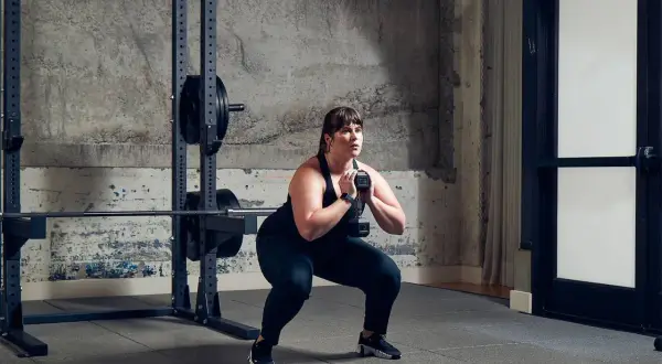 Frau macht einen Goblet Squat mit Kurzhantel als Teil ihres Metcon Workouts.