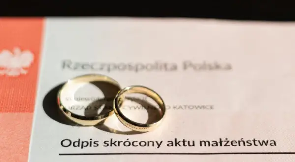 Złote obrączki na odpisie skróconym aktu małżeństwa. Dokument potwierdza zawarcie związku, jak wygląda akt ślubu.
