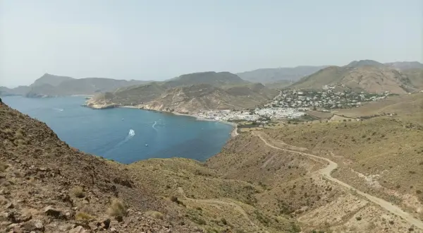 Vista panorámica de la costa de Almería, con el mar azul, un pueblo blanco y el paisaje árido del cerro negro.