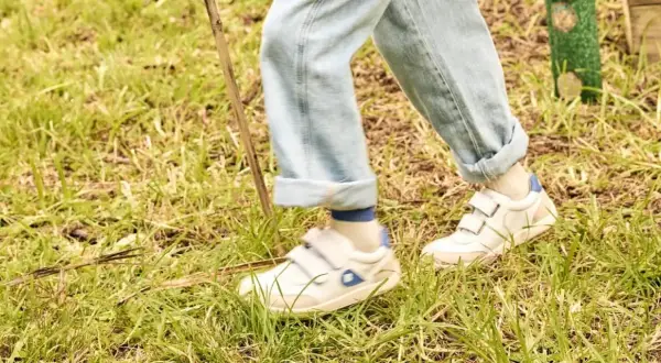 Białe sneakersy na rzepy, idealne na spacer po trawie. To wygodne buty dla aktywnych.