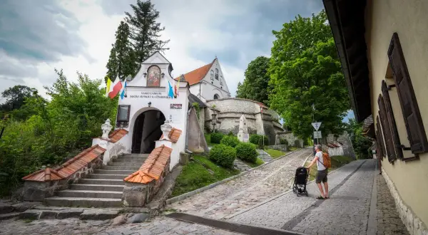 Droga do Sanktuarium Matki Bożej w Trzcińcu Lubelskim. Mężczyzna z wózkiem idzie brukowaną uliczką.