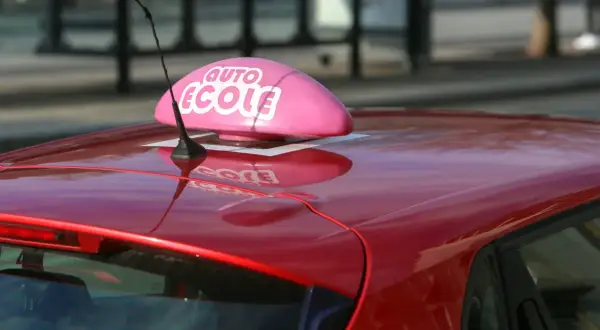 Voiture rouge d'auto-école, prête pour un jeune conducteur responsable qui vise le permis à 17 ans.