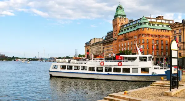 En vit passagerarbåt ligger vid kajen i Stockholm. En båttur här ger fin utsikt över stadens vackra byggnader och vattnet.