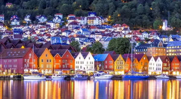 Bunte Holzhäuser am Wasser, ein Traum für Bergen Sightseeing. Boote spiegeln sich im Abendlicht.