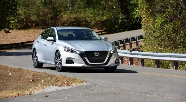 Srebrny Nissan Altima na krętej drodze, gotowy do przeniesienia własności samochodu.