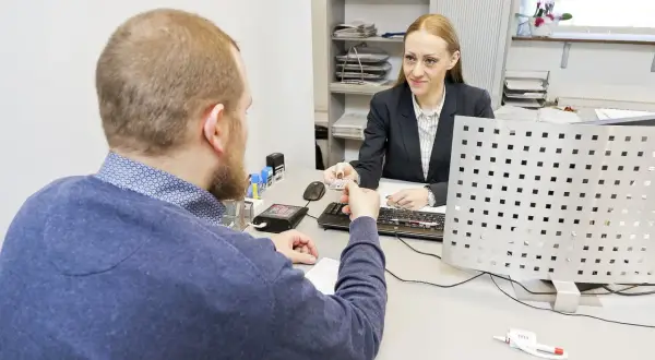 Mężczyzna przekazuje dokument do wymiany prawa jazdy urzędniczce.