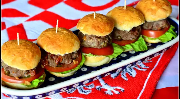 Pięć apetycznych mini burgery na zimno, ułożonych na talerzu, z pomidorami, sałatą i mięsem. Idealne na letnie przyjęcie.