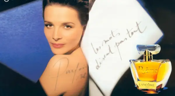 Kobieta z subtelnym uśmiechem, flakonik perfum Lancôme Poême i odręczne pismo na białym tle.