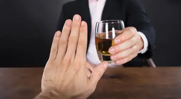Mężczyzna odrzuca kieliszek alkoholu, zastanawiając się, jaki alkohol ma najmniej kalorii.
