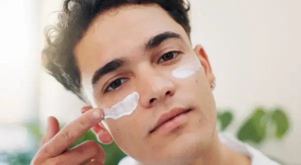 Mann trägt Gesichtscreme auf. SPF 15 Bedeutung: Schutz vor Sonneneinstrahlung für die Haut.