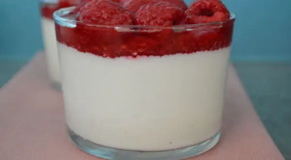 Délicieuse panna cotta à la vanille, surmontée d'un coulis de framboise et de framboises fraîches. Un dessert léger et fruité.