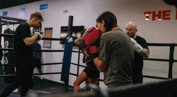 Intense soviet boxing training session in a ring. A coach observes as two boxers spar, their gloves a blur of motion.