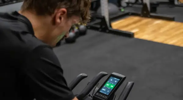Mężczyzna na rowerze stacjonarnym sprawdza dane treningowe. Czy to już czas na test FTP?