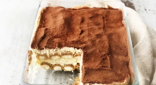 Pyszne tiramisu w szklanej formie, posypane kakao. Idealne, gdy wiesz, jak sparzyć jajka do tiramisu.
