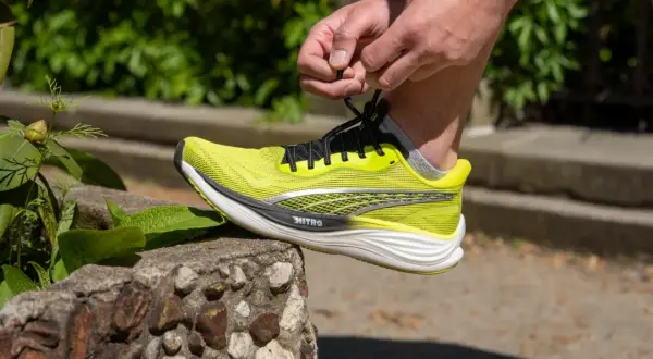 Dłoń wiąże sznurówki jaskrawożółtego buta Puma Deviate Nitro 3, gotowego na bieg.