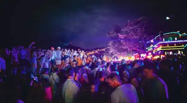 Stor folkmassa festar under neonljus på Koh Phangan, Thailand.