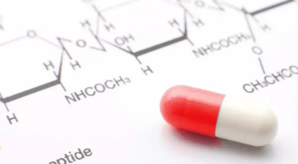 Kapsułka na tle wzoru chemicznego. Może to być element testu na narkotyki lub badania leków.