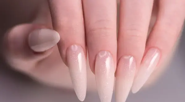 Delikatny manicure baby boomer na długich paznokciach, z subtelnym brokatem.