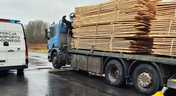 Samochód Inspekcji Transportu Drogowego obok ciężarówki z drewnem.