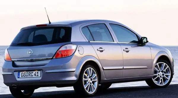 Srebrny Opel Astra H 1.6 benzyna z widokiem z tyłu, zaparkowany nad morzem.