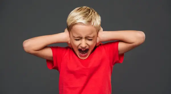 Bambino con capelli biondi, occhi chiusi e bocca spalancata, copre le orecchie con le mani. Rappresenta una crisi di rabbia nei bambini di 10 anni.