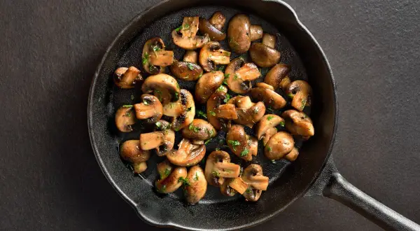 Stekta champinjoner i gjutjärnspanna, perfekt för ett snabbt svamp recept. Garnerade med persilja.