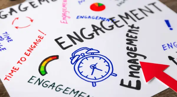 Mappa mentale con la parola "ENGAGEMENT" in grande, circondata da icone e frasi che stimolano l'audience engagement: sveglia, freccia rossa, grafico a torta.
