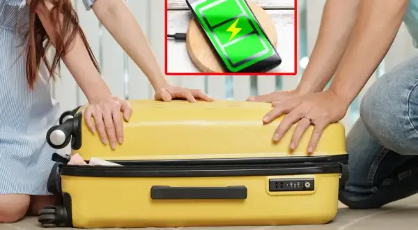 Para podróżnych zamyka żółtą walizkę. Telefon na ładowarce bezprzewodowej pokazuje pełną baterię, idealny na podróż z Wizzair, gdzie przyda się powerbank.
