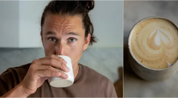 Man med blå ögon dricker en vacker latte hemma. Kaffet har ett hjärtformat mönster i skummet.