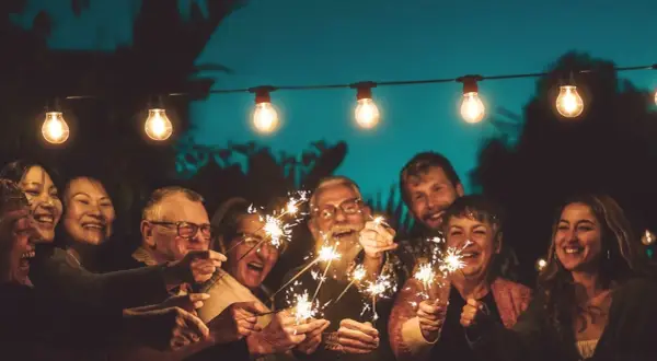 Familie feiert mit Wunderkerzen unter Lichterketten. Ein Lächeln, das die Bedeutung eines 75. Hochzeitstages widerspiegelt.