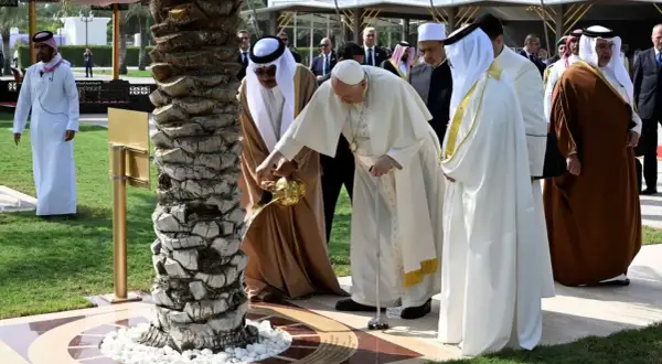 Papież Franciszek i przywódca Zjednoczonych Emiratów Arabskich wspólnie podlewają drzewo. W tle widać ludzi w tradycyjnych strojach, jakby na spotkaniu z muezinem.